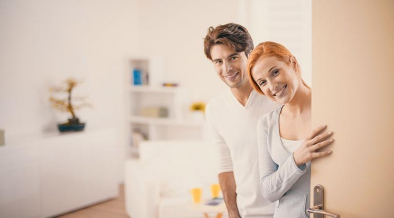 Image d'un couple accueillant ouvrant la porte pour illustrer l'achat immobilier entre particuliers