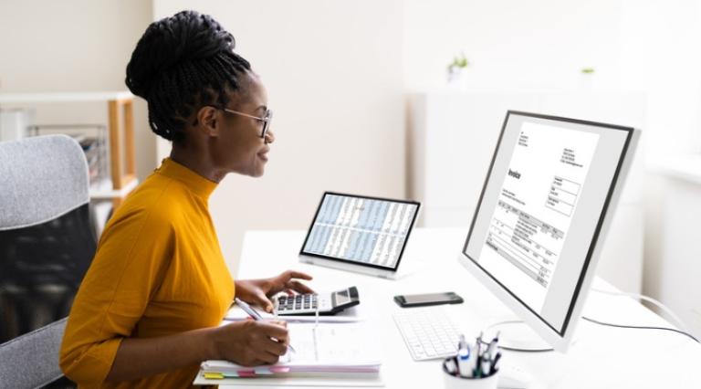 Photo d'une femme devant un ordinateur avec une calculatrice pour revendre ses parts de SCPI de plus value