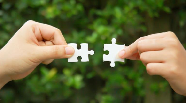 Deux mains assemblant 2 morceaux de puzzle pour symboliser le financement participatif immobilier
